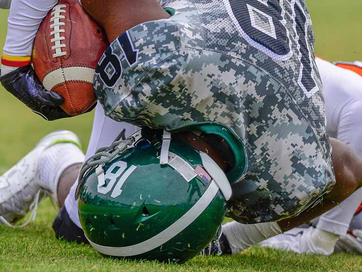 Young football player hits his head on the ground after being tackled. These head injuries could lead to CTE.